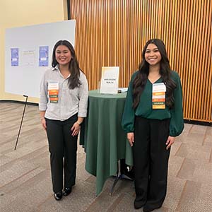 Two people in business attire standing in front of a poster