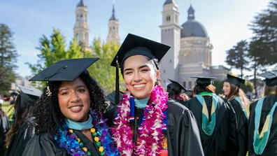 Two USF graduates posing in front of St. Ignatius