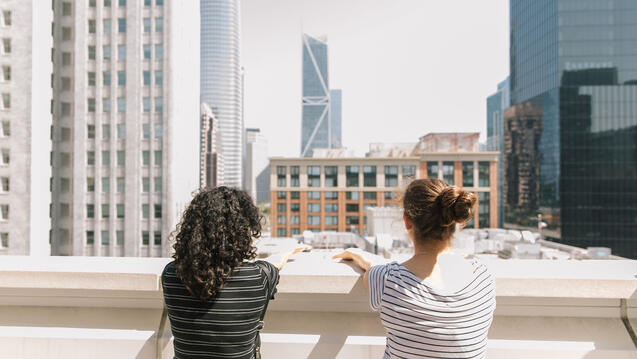 Students on a roof look at the city skyline.