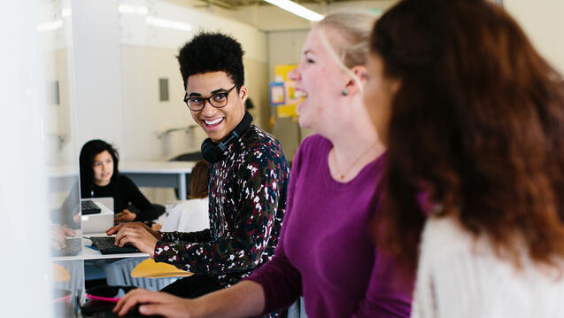 Group of students in a lounge using public computers to work on a project.