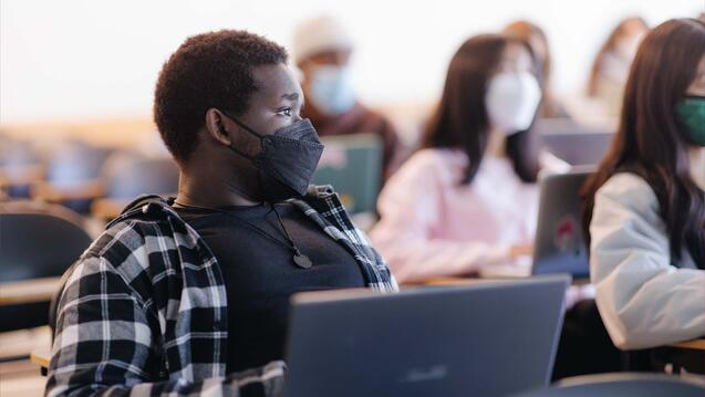 Student leans back listening in class