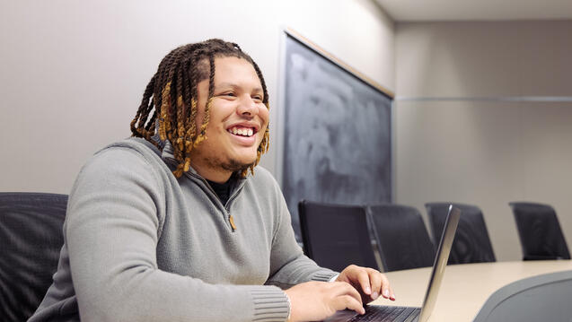 student sitting in classroom in front of laptop