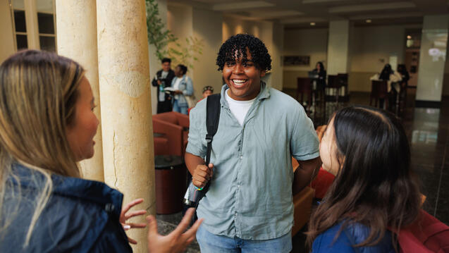 Three USF students chatting on campus, smiling