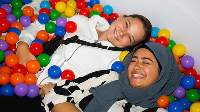 two students laying in ball pit