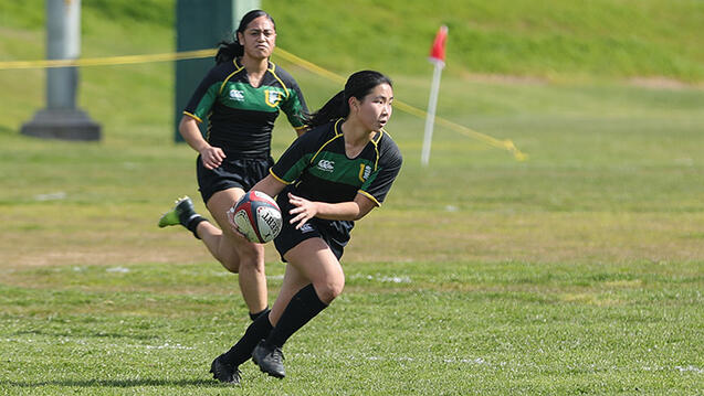 student runs with rugby ball