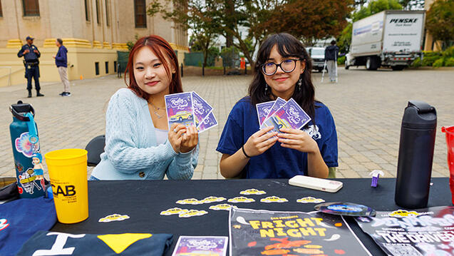 students hold flyers behind table