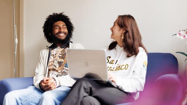 Two people sitting on the couch looking at each other