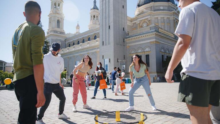 Students playing spike ball around a circular net in Gleeson Plaza