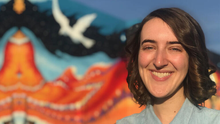 Ali Hofer in front of a colorful mural.