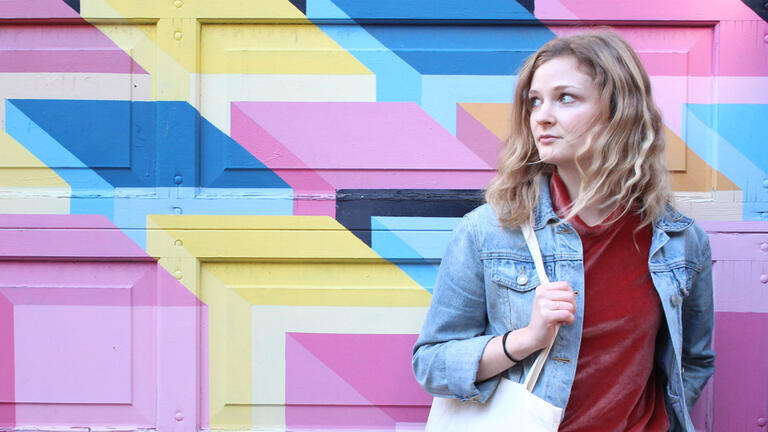 Madeline Warner in front of a mural.