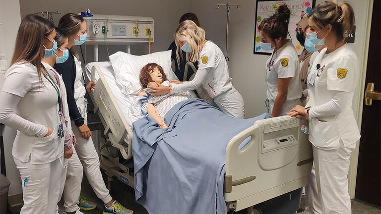 group of nursing students interact with manikin