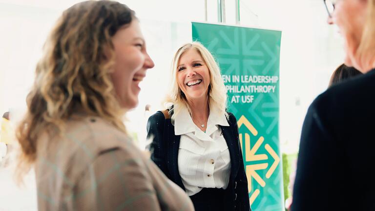 Three people smiling in conversation