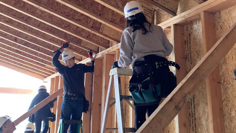 SOM students on ladders at Habitat build