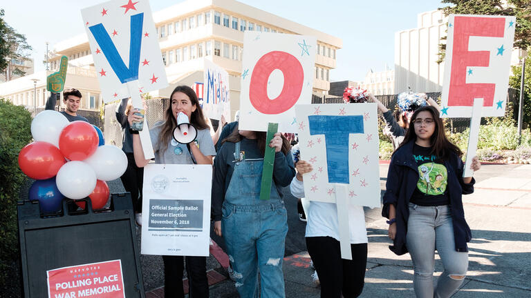 Students try to engage the community, holding signs that read VOTE