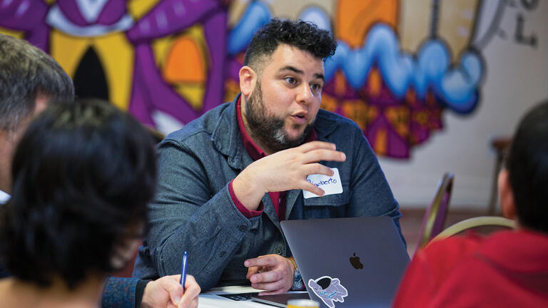 Community leader talks to people at a table at an event.