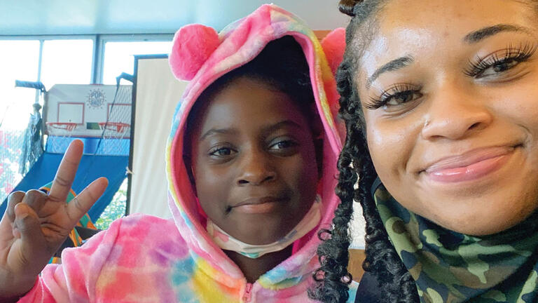 Student in a colorful costume poses with a teacher.