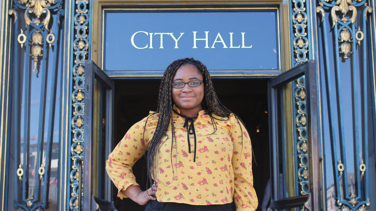 Student stands in front of an elaborate door at SF City Hall