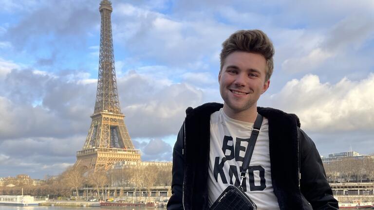 a student standing in view of the Eiffel tower