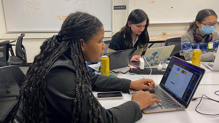 Students work on their laptops at a table