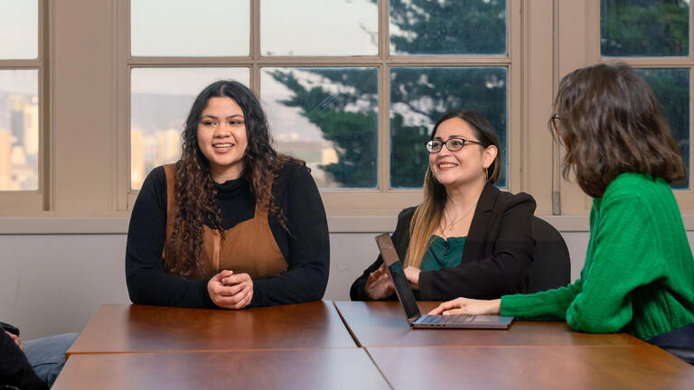 Three USF students in class engaging in discussion