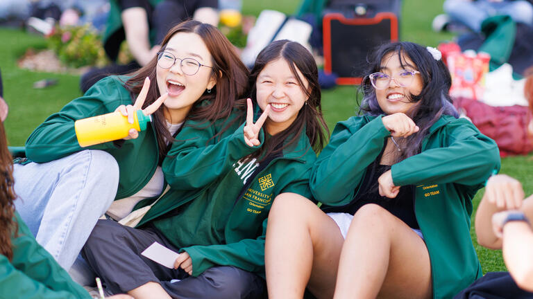 Three students hanging out on the grass.