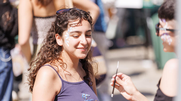 student gets her face painted at day of the dons