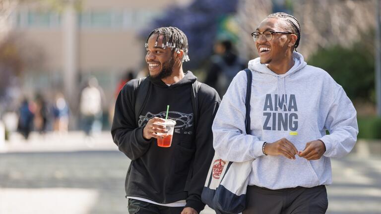 two students walking and laughing together on usf campus