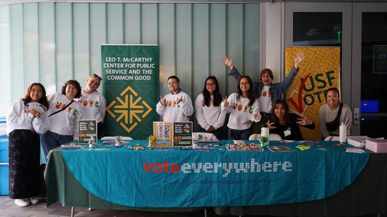 students sitting at table registering people to vote