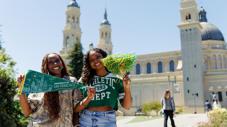 Two USF students posing with USF merch