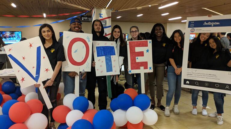 students holding VOTE sign with balloons