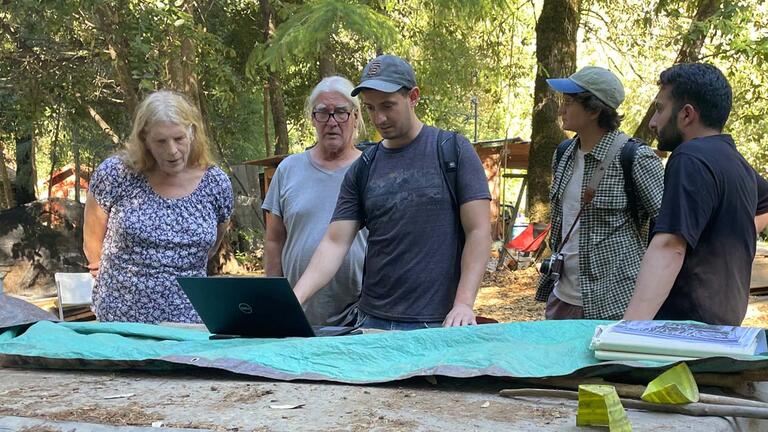 students and community partners review building plans in the woods