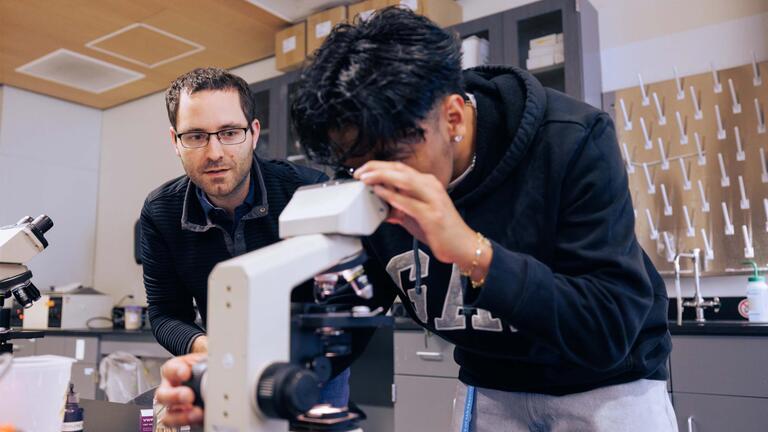 faculty mentoring student looking in microscope