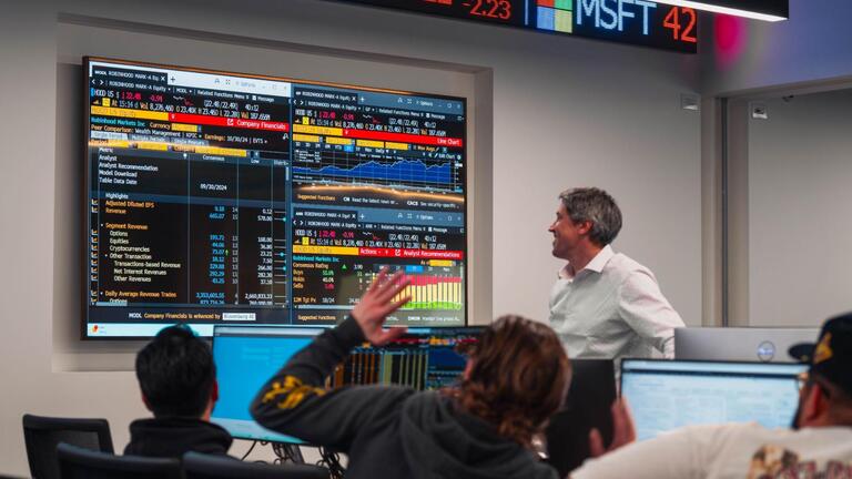 Professor looking at the stock market on a screen