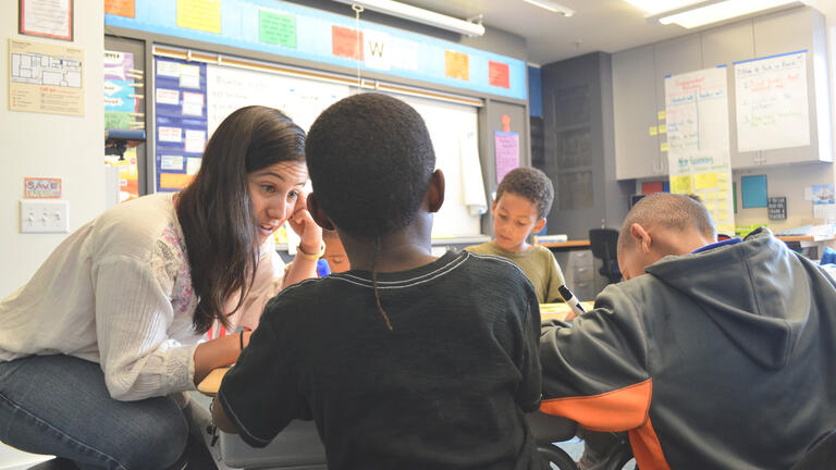 teacher helps young students in class
