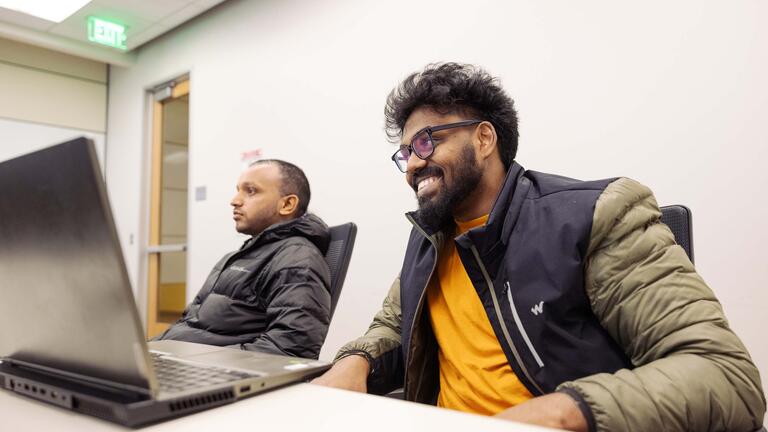 Two students with laptops in a classroom