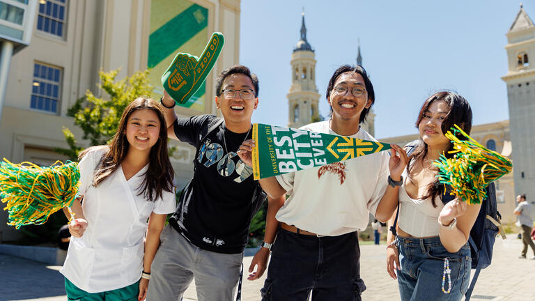 Students smiling and holding up USF spirit memorabilia