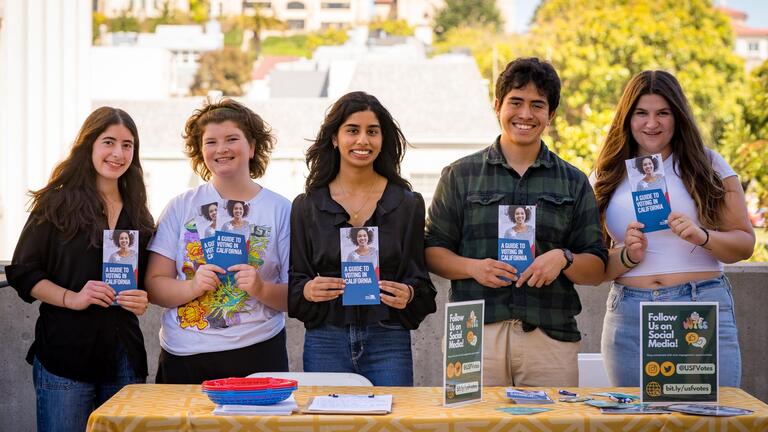 five students at a table holding Voting in California brochures