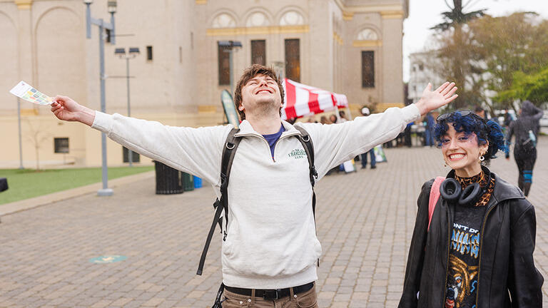 Student looking up at the sky with arms out