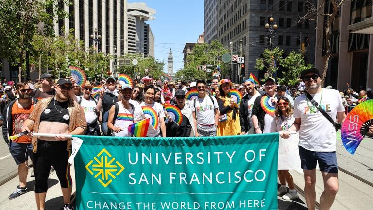 Group of people holding the University of San Francisco banner and marching in the Pride parade
