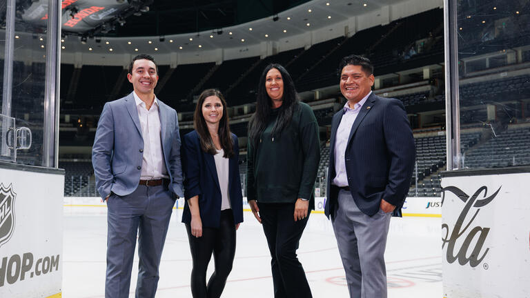 Four sport management students posing in front of ice rink