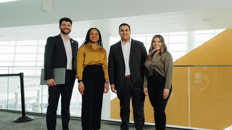 Four people posing in business attire