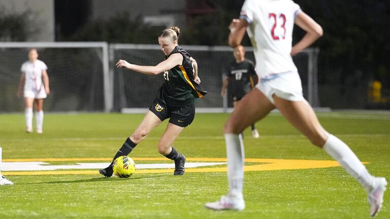 student runs with soccer ball during match