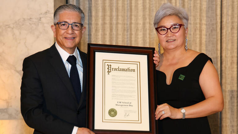 people holding up plaque for school of management