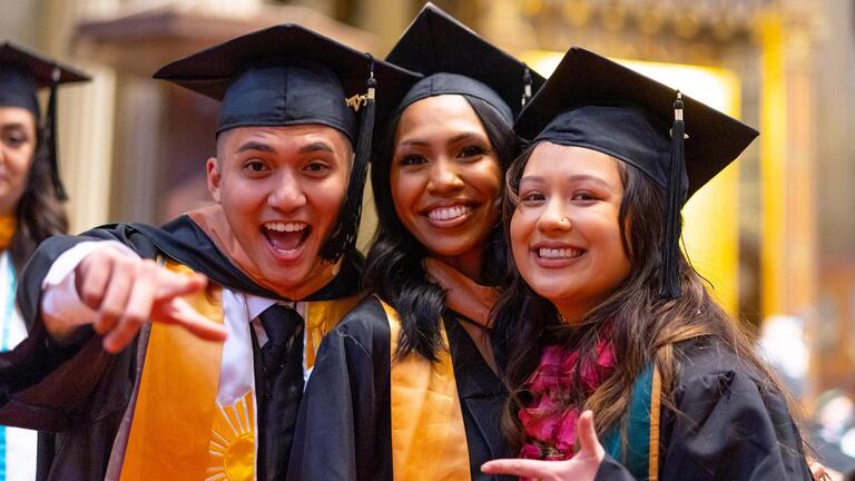 students smiling with their graduation caps and gowns