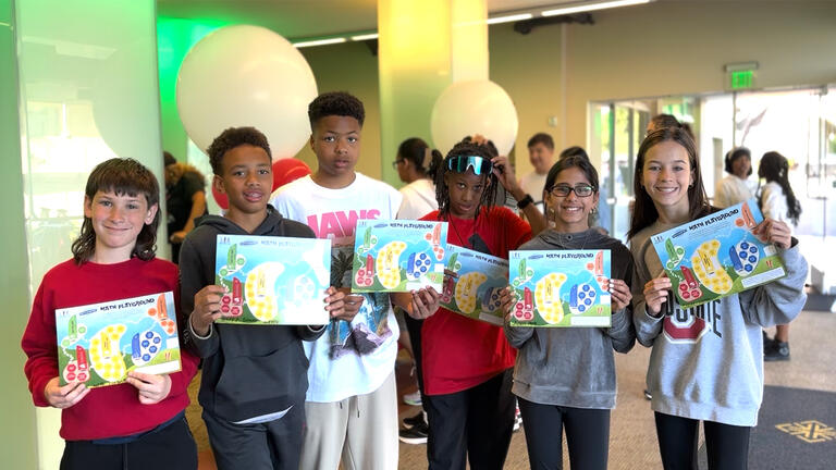 Young students holding class project and smiling