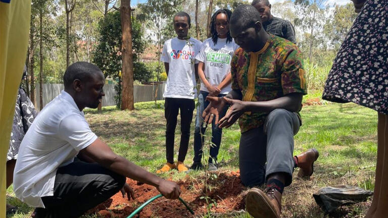 Barwendé Médard Sané gesturing to a plant while speaking to children