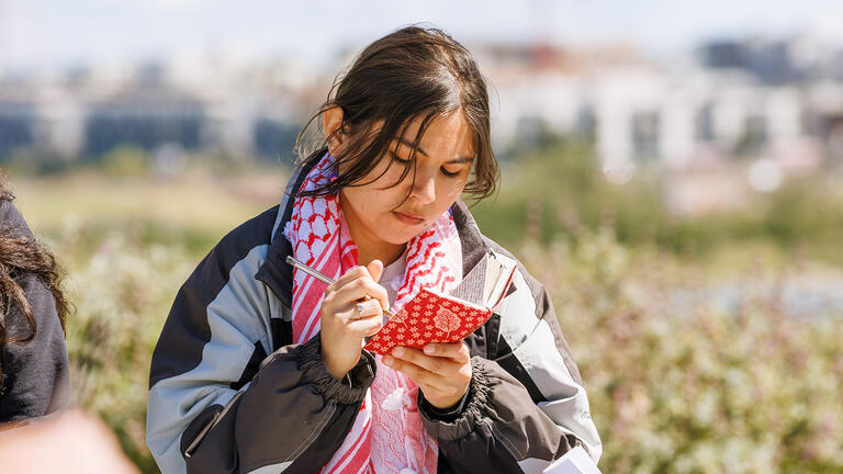 Student jots notes in her journal in the Bayview neighborhood of San Francisco