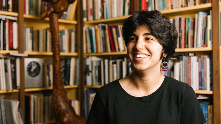 student sitting in front of a bookcase