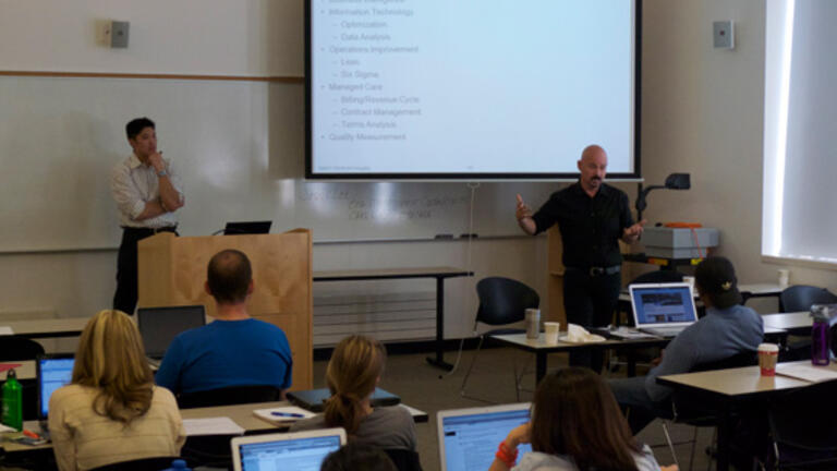 Professor stands behind podium in classroom