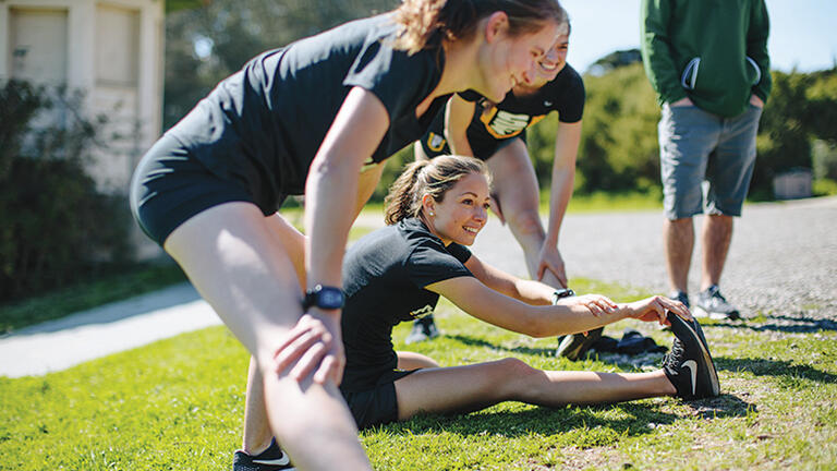 Women&#039;s cross country team members stretch